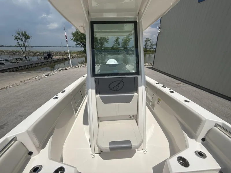 Slide: The Image of 2025 Sailfish 232 CC boat interior with seating and cup holders, dockside view. - 16