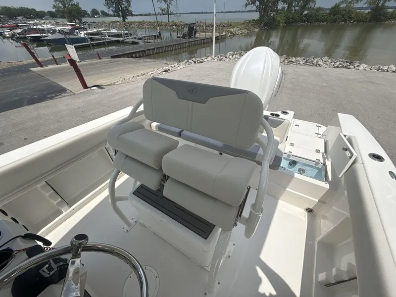 Slide: The Image of 2025 Sailfish 232 CC boat interior with helm seating, docked near a marina. - 9