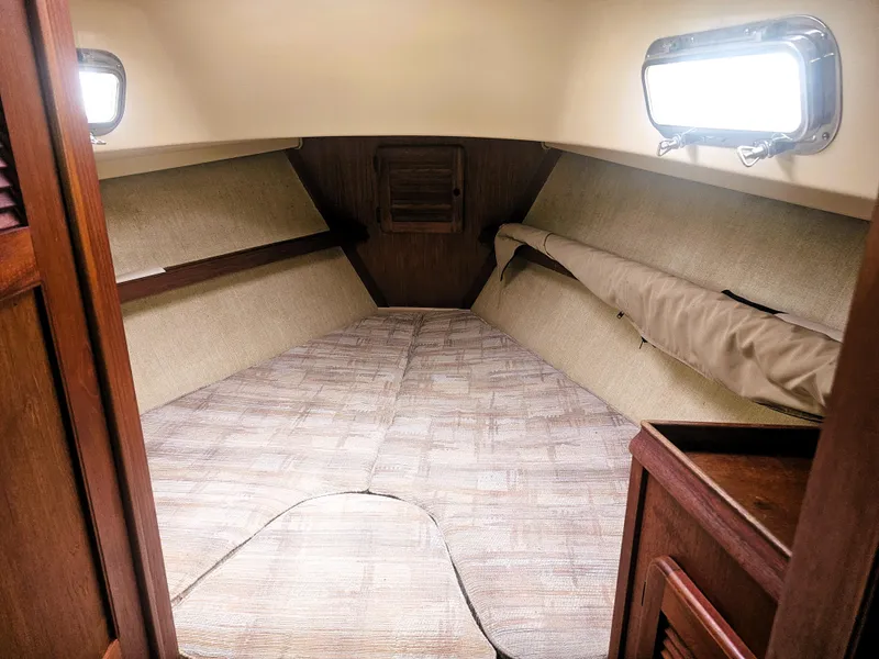 Slide: The Image of 1990 Island Packet 35 sailboat interior cabin with cozy sleeping area and wooden accents. - 13