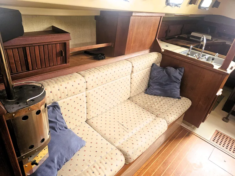 Slide: The Image of 1990 Island Packet 35 interior with cozy seating, wooden cabinetry, and a compact kitchen area. - 2
