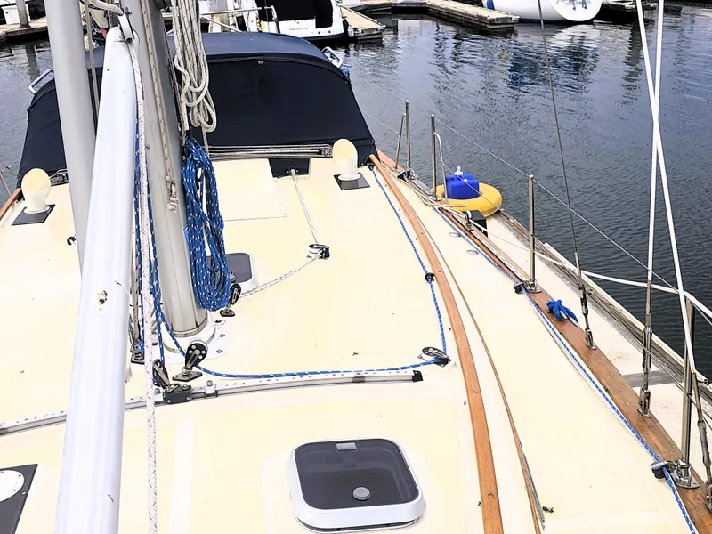 Slide: The Image of 1990 Island Packet 35 sailboat deck with ropes and hatches, docked at marina. - 20