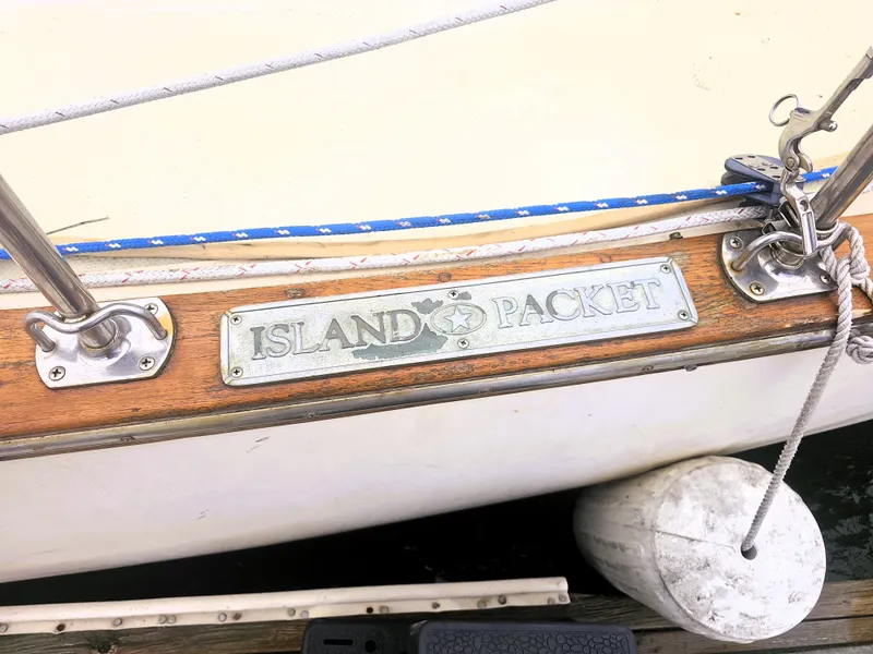 Slide: The Image of 1990 Island Packet 35 sailboat with nameplate, docked with visible fender. - 3