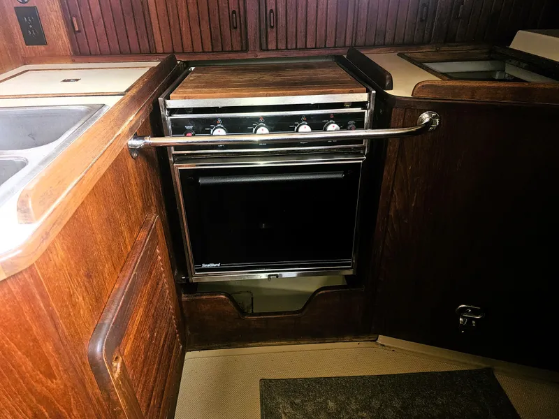 Slide: The Image of 1990 Island Packet 35 yacht kitchen with wooden cabinetry and stainless steel oven. - 5