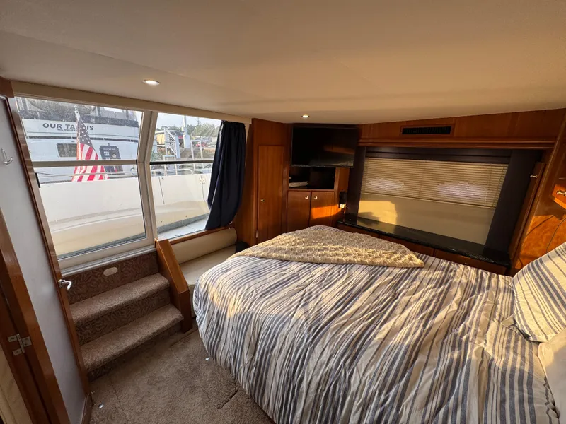 Slide: The Image of Interior of 2000 Carver 504 Cockpit Motor Yacht bedroom with striped bedding and large windows. - 42