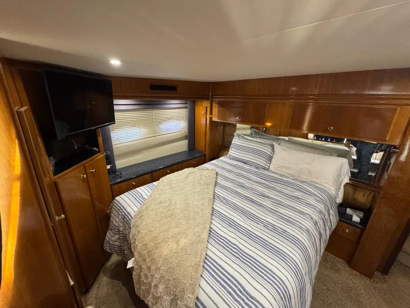 Slide: The Image of Luxurious bedroom in 2000 Carver 504 Cockpit Motor Yacht with striped bedding and wood paneling. - 44