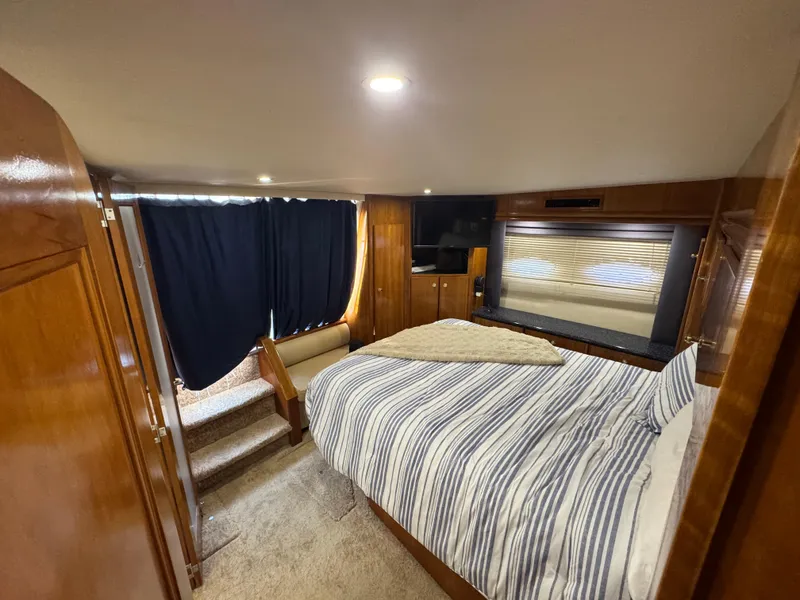 Slide: The Image of Luxurious bedroom in 2000 Carver 504 Cockpit Motor Yacht with striped bedding and wood accents. - 45