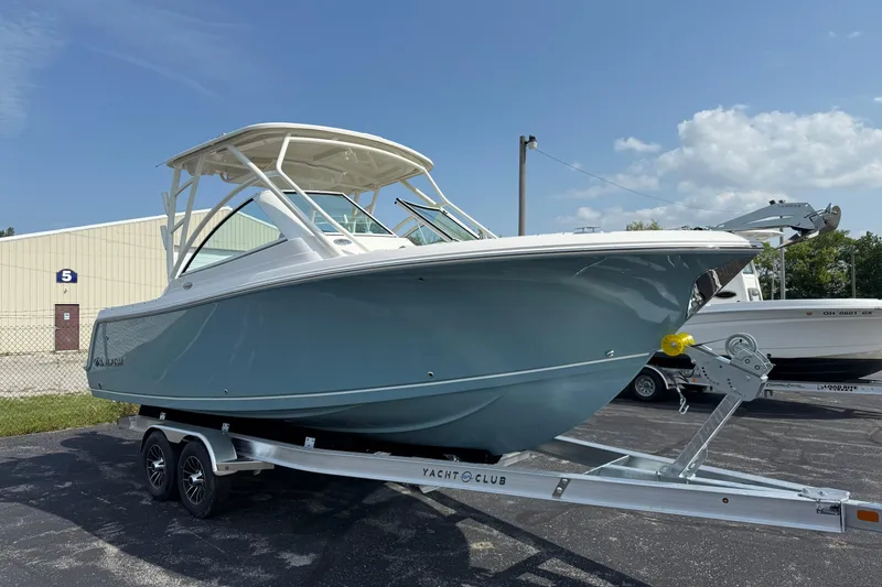 Slide: The Image of 2025 Sailfish 245 DC boat on trailer, parked outdoors under clear sky. - 2