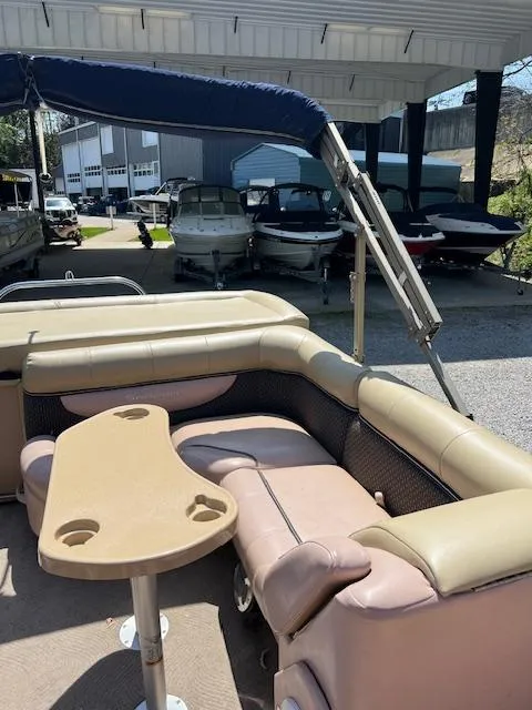 Slide: The Image of 2008 Godfrey SANPAN 2500 DC pontoon boat with beige seating and table, docked under shelter. - 6