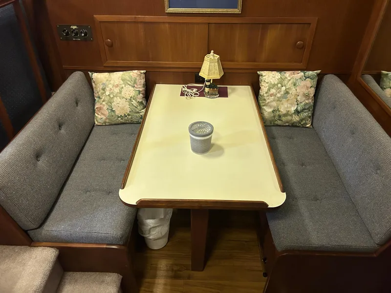 Slide: The Image of 1987 Chris-Craft 362 Catalina interior with cozy dining area, floral cushions, and wooden accents. - 23
