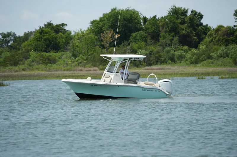 Slide: The Image of 2023 Key West 219 FS boat cruising on a calm lake with lush greenery. - 11