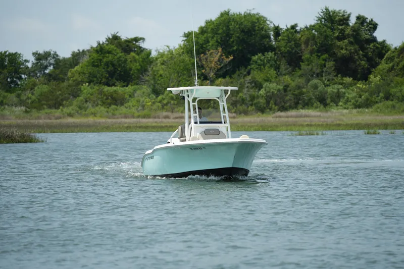 Slide: The Image of 2023 Key West 219 FS boat cruising on a serene lake with lush greenery. - 12