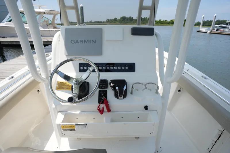Slide: The Image of 2023 Key West 219 FS boat console with Garmin system, steering wheel, and controls by the water. - 19
