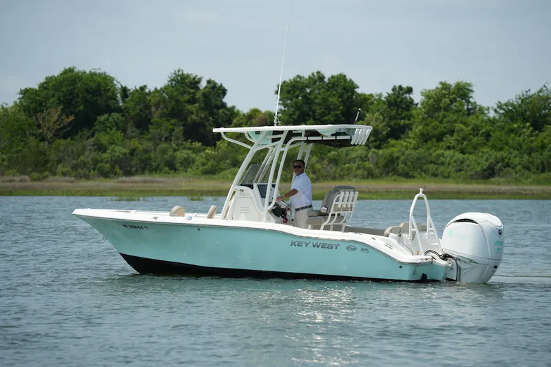Slide: The Image of 2023 Key West 219 FS boat on calm water with lush green background. - 2