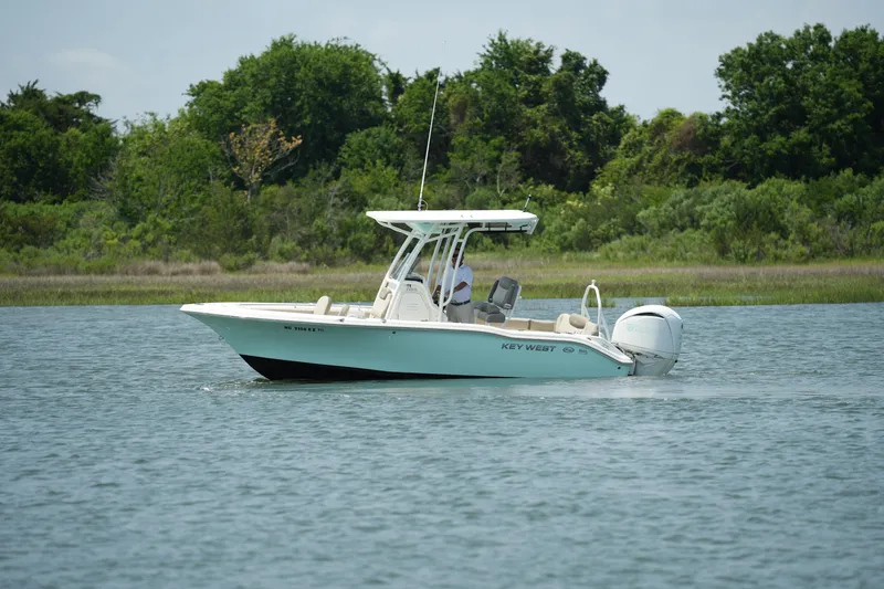 Slide: The Image of 2023 Key West 219 FS boat cruising on a calm lake with lush green trees. - 4