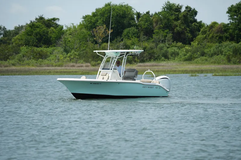 Slide: The Image of 2023 Key West 219 FS boat on calm water with lush green trees in the background. - 5