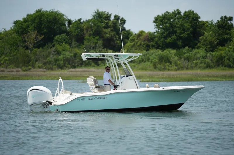 Slide: The Image of 2023 Key West 219 FS boat cruising on a calm lake with lush greenery. - 6
