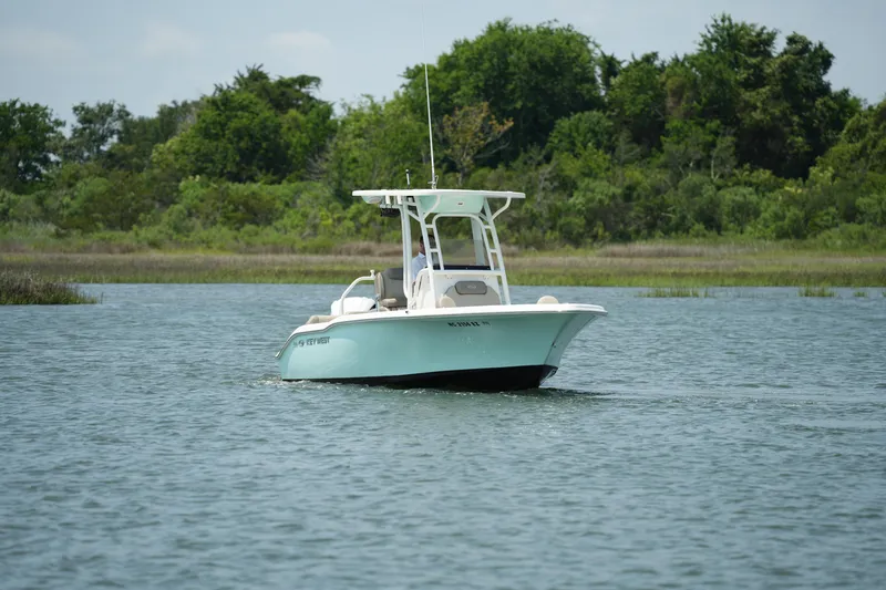 Slide: The Image of 2023 Key West 219 FS boat cruising on a calm lake with lush greenery in the background. - 8