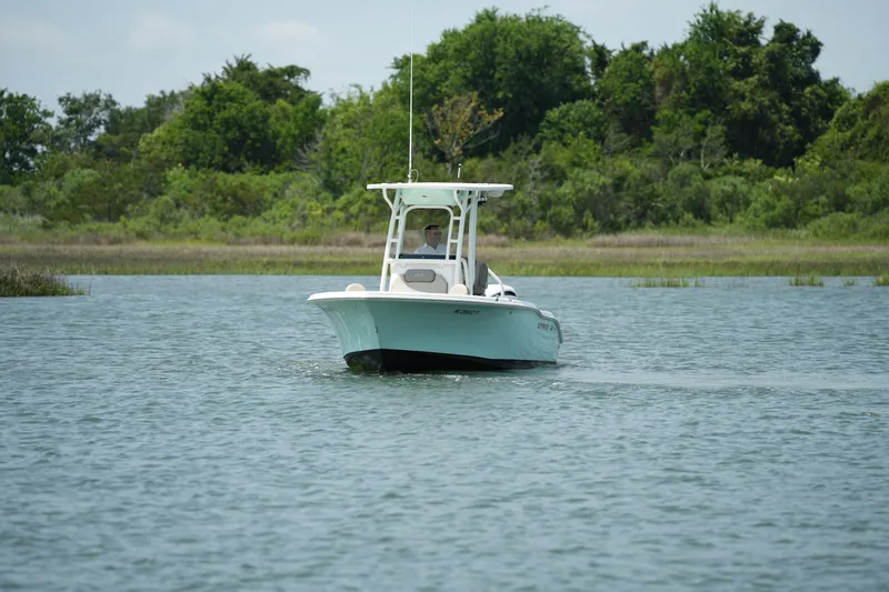 Slide: The Image of 2023 Key West 219 FS boat cruising on a calm lake with lush greenery. - 9