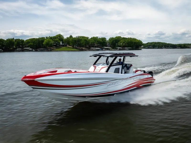 Slide: The Image of 2017 Sunsation 34 CCX speedboat cruising on a lake with lush green shoreline. - 12
