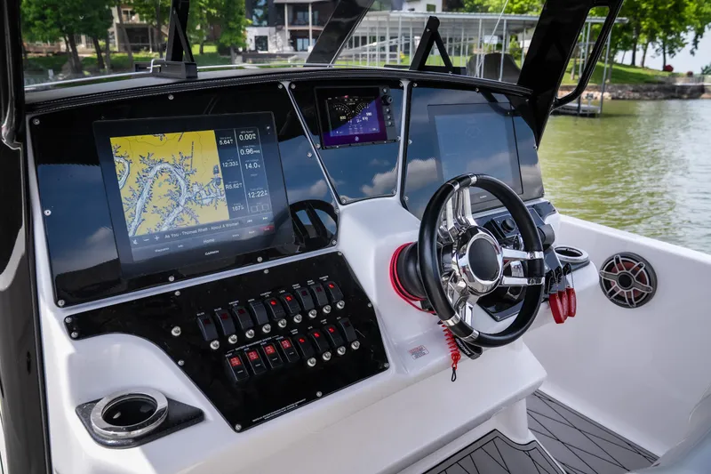 Slide: The Image of 2017 Sunsation 34 CCX boat dashboard with navigation screens and steering wheel, docked by a lake. - 19