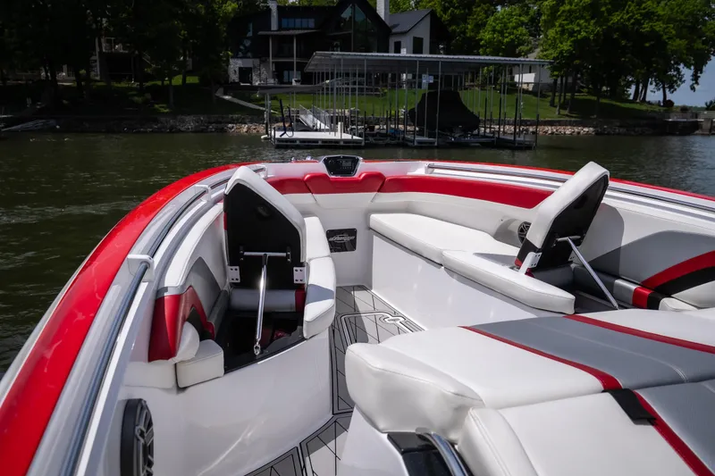 Slide: The Image of 2017 Sunsation 34 CCX boat interior with red and white seating, docked near a lakeside house. - 22