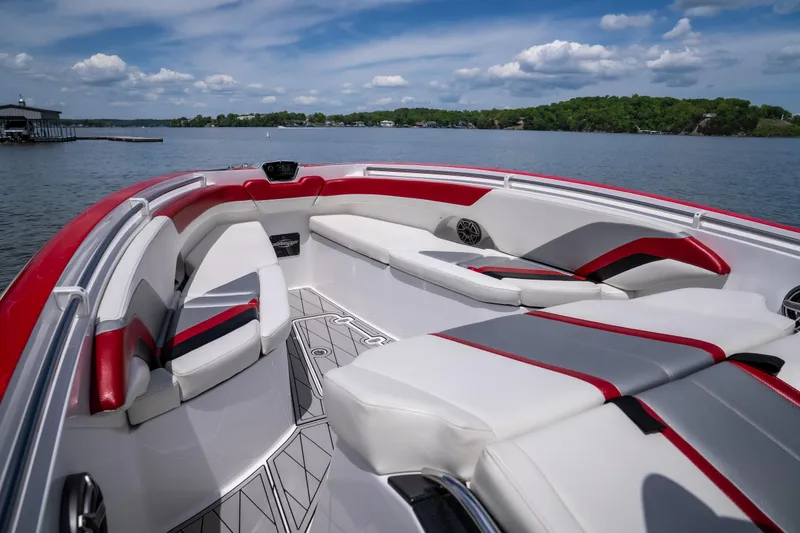Slide: The Image of 2017 Sunsation 34 CCX boat interior with red and white seating on a calm lake. - 26