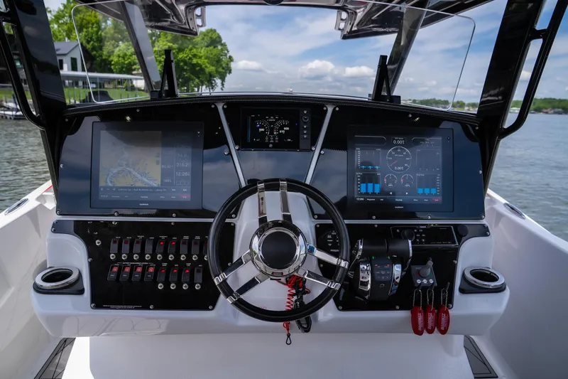 Slide: The Image of 2017 Sunsation 34 CCX boat dashboard with dual screens and steering wheel on a sunny day. - 38