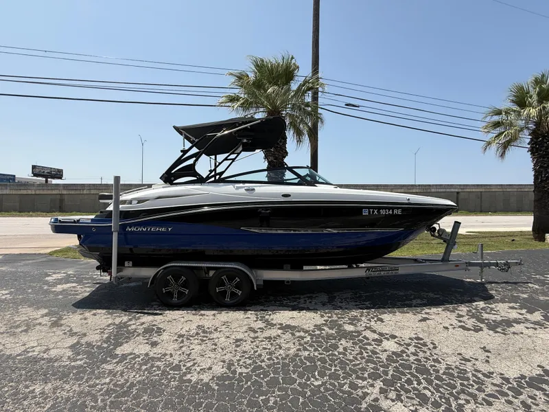 Slide: The Image of 2019 Monterey MX6 SURF boat on trailer, parked outdoors with palm trees in the background. - 32