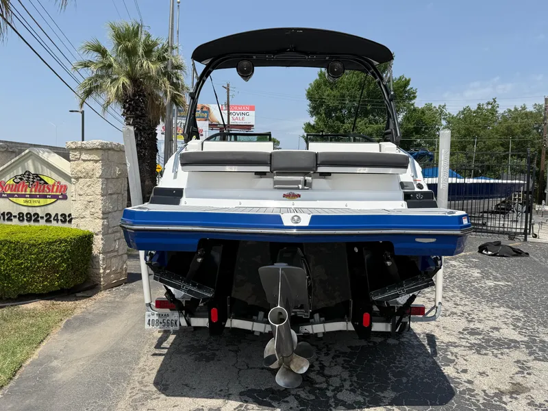 Slide: The Image of 2019 Monterey MX6 SURF boat, rear view, parked outdoors with palm trees and signage. - 34