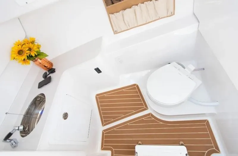 Slide: The Image of 2025 Southport 33 DC boat bathroom with toilet, sink, and sunflowers in a vase. - 3