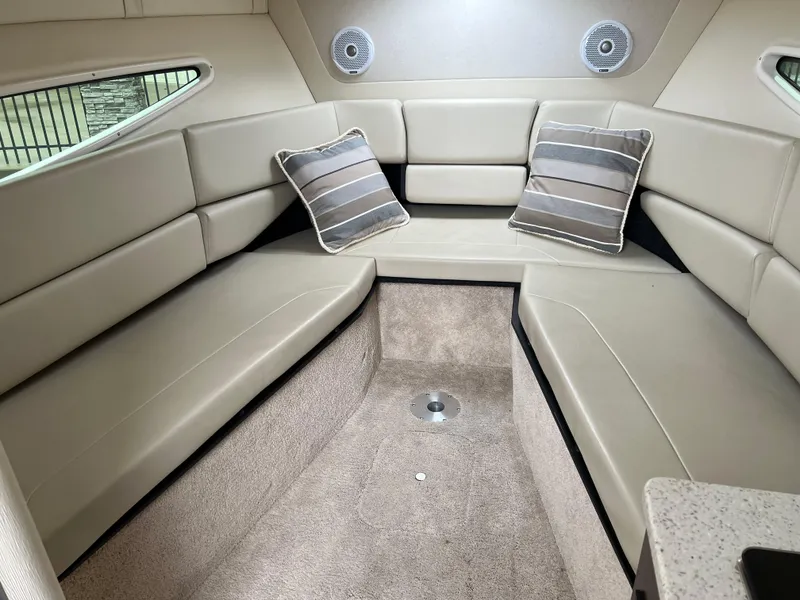 Slide: The Image of 2018 Regal Commodore 258 boat interior with white cushioned seating and beige accents. - 14