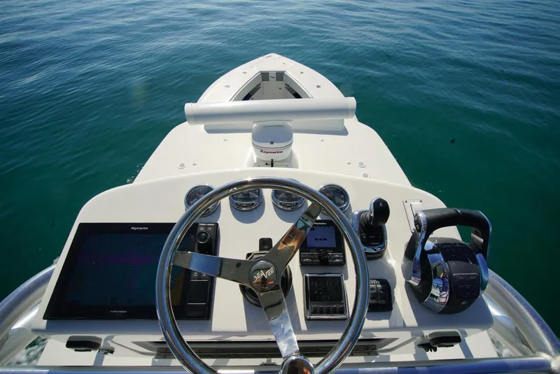 Slide: The Image of 2018 SeaVee 390Z boat helm with steering wheel and navigation controls on calm water. - 8