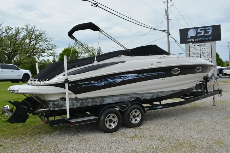 The Image of 2007 Crownline 275 CCR boat on trailer, parked outdoors near dealership sign. - 0