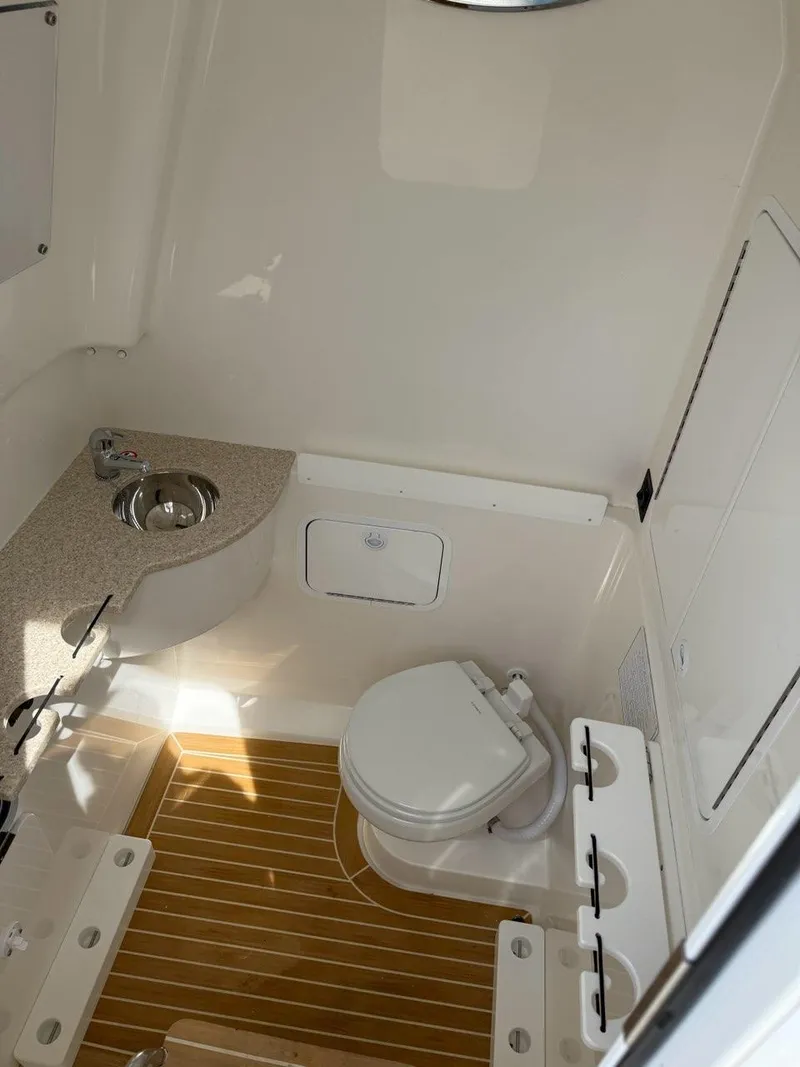 Slide: The Image of 2021 Regulator 31 boat interior with compact bathroom, featuring a toilet and sink. - 8