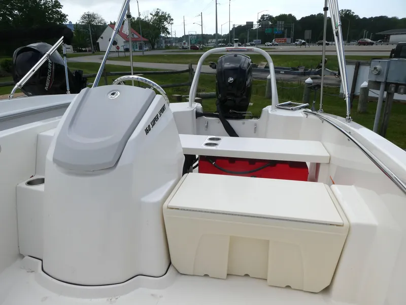Slide: The Image of 2025 Boston Whaler 160 Super Sport boat interior with seating and motor, parked outdoors. - 5