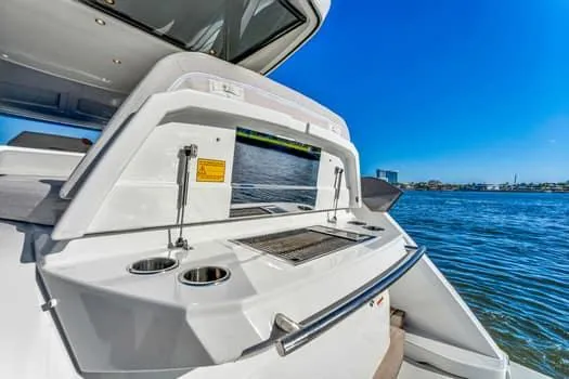 Slide: The Image of 2023 Beneteau Gran Turismo 45 yacht with outdoor kitchen, overlooking serene blue waters. - 11