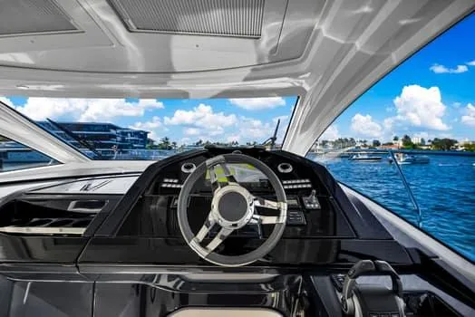 Slide: The Image of 2023 Beneteau Gran Turismo 45 yacht cockpit with steering wheel, overlooking serene blue waters. - 22