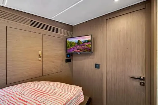 Slide: The Image of 2023 Beneteau Gran Turismo 45 cabin interior with TV and striped bedding. - 34