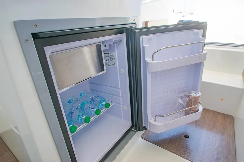 Slide: The Image of Mini fridge inside 2021 Beneteau Antares 8 boat, stocked with water bottles. - 12