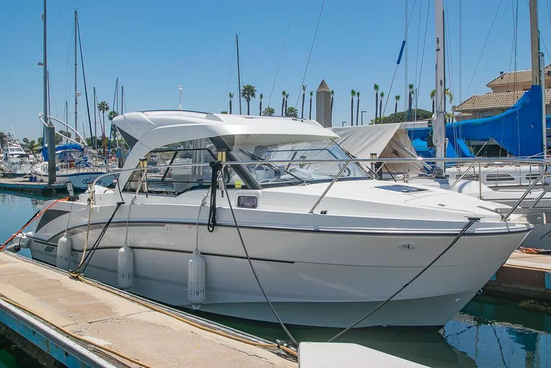 Slide: The Image of 2021 Beneteau Antares 8 docked at marina, clear sky, sailboats in background. - 2