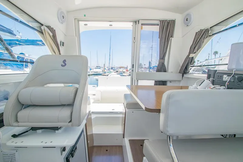 Slide: The Image of Interior of 2021 Beneteau Antares 8 boat, featuring seating and table with marina view. - 20