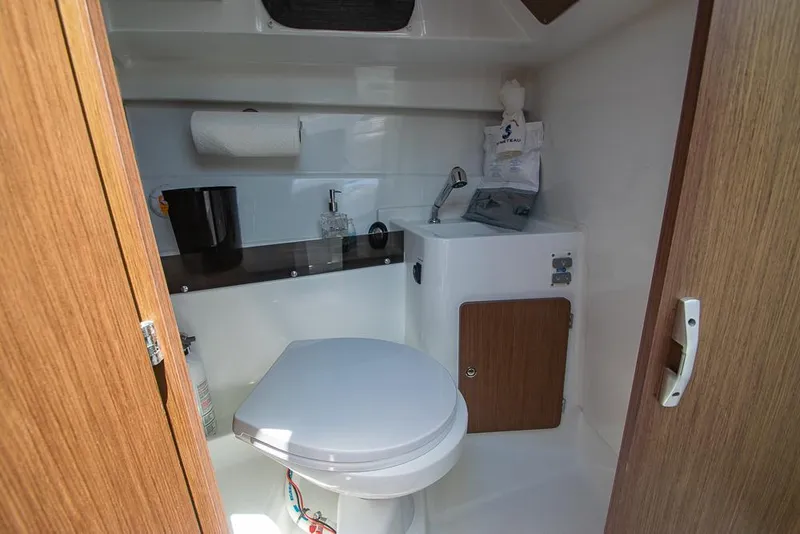 Slide: The Image of 2021 Beneteau Antares 8 boat bathroom with toilet, sink, and wooden accents. - 28