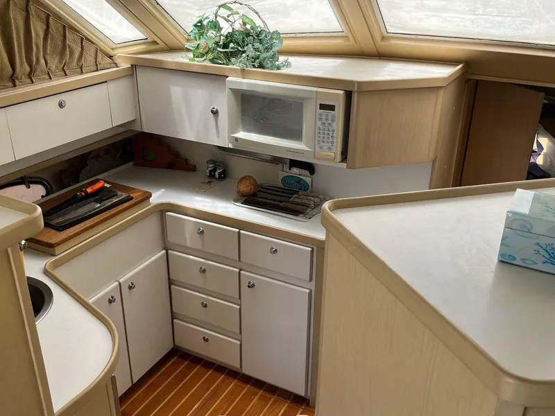 Slide: The Image of 1994 Tiara Yachts 3600 Convertible Sportfish kitchen with white cabinets and wood flooring. - 5