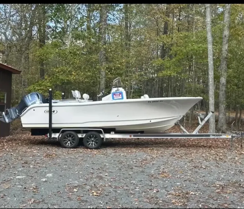 The Image of 2021 Sea Hunt Triton 225 boat on trailer, parked in wooded area, for sale sign visible. - 1