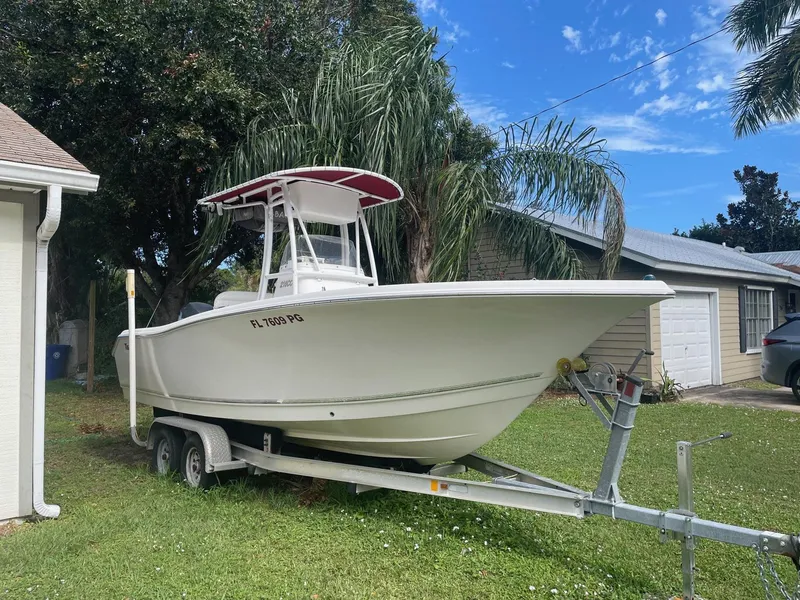 The Image of 2012 Tidewater 220 CC Adventure boat on trailer, parked on grass near house. - 1