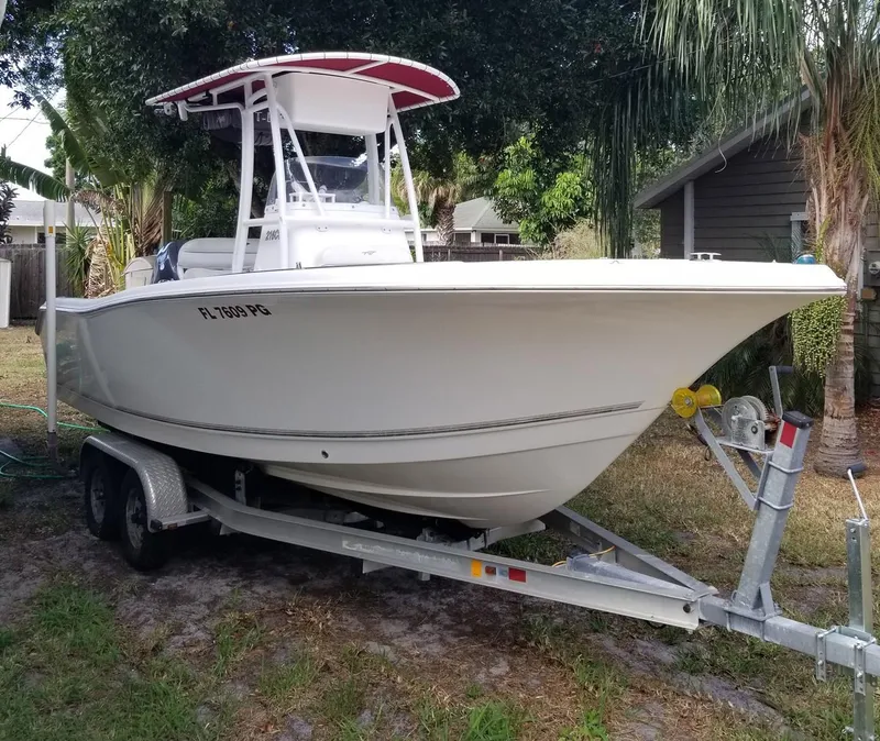 Slide: The Image of 2012 Tidewater 220 CC Adventure boat on trailer, parked outdoors near trees. - 10