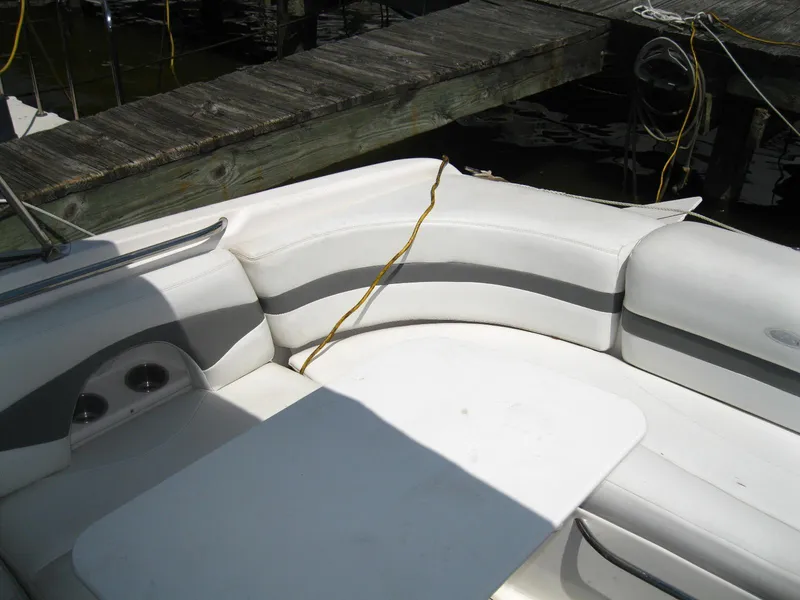 Slide: The Image of 2005 Chaparral 280 SSi boat interior with white seating and table near dock. - 8