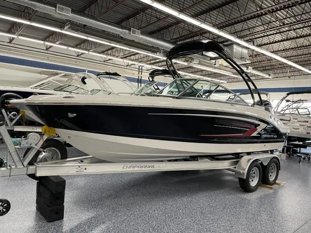 The Image of 2025 Chaparral 21 SSi OB boat on trailer in showroom, sleek design, black and white exterior. - 0