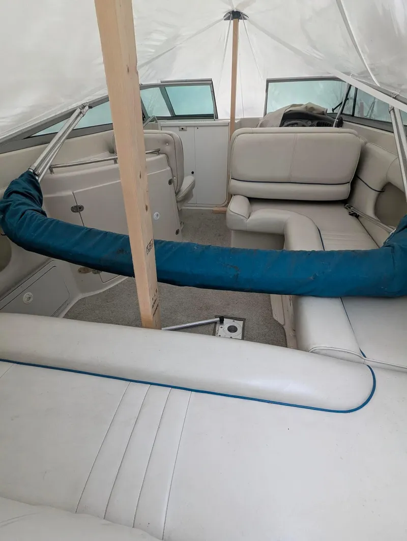 Slide: The Image of 1999 Crownline 266 CCR boat interior with white seating and protective cover. - 14
