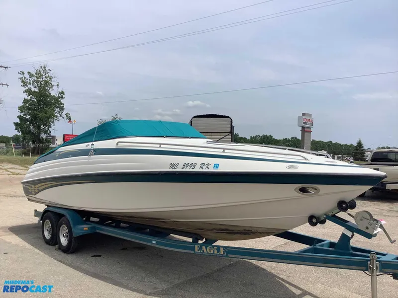 Slide: The Image of 1999 Crownline 266 CCR boat on trailer, parked outdoors, with teal cover. - 3